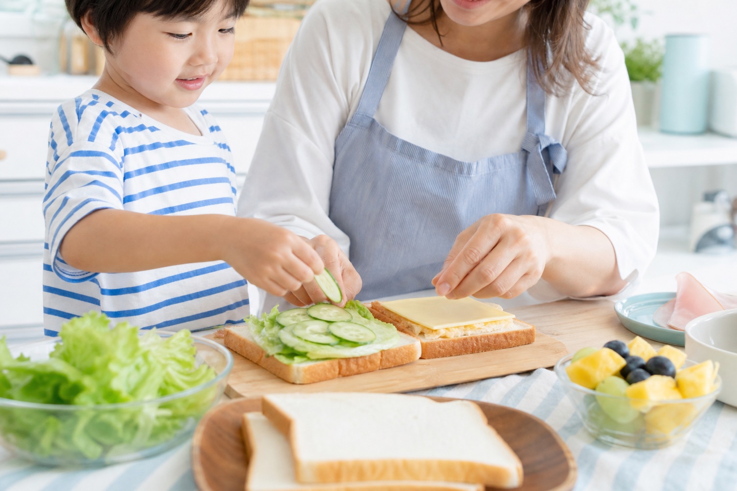親子でサンドイッチの具材をのせている様子