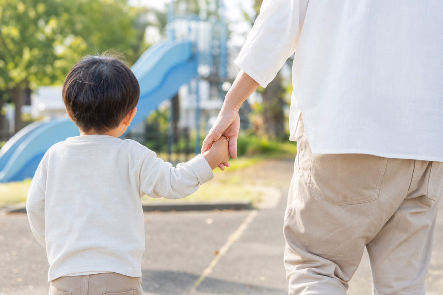 公園をあとにして手をつないで歩く子どもと大人