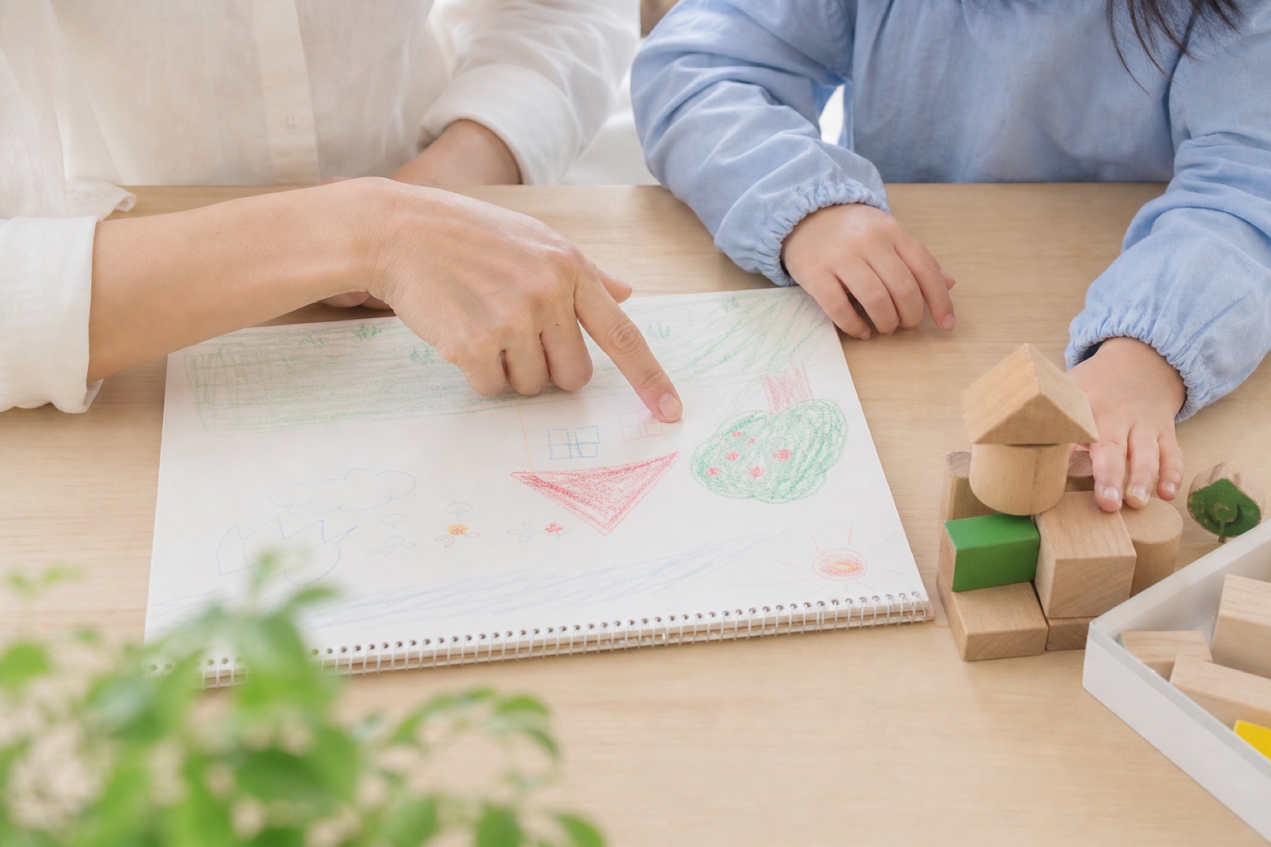 子どもの絵と積み木を親子で一緒に見ている手元