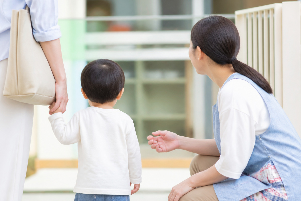 保育園の入り口で手をつなぐ親子